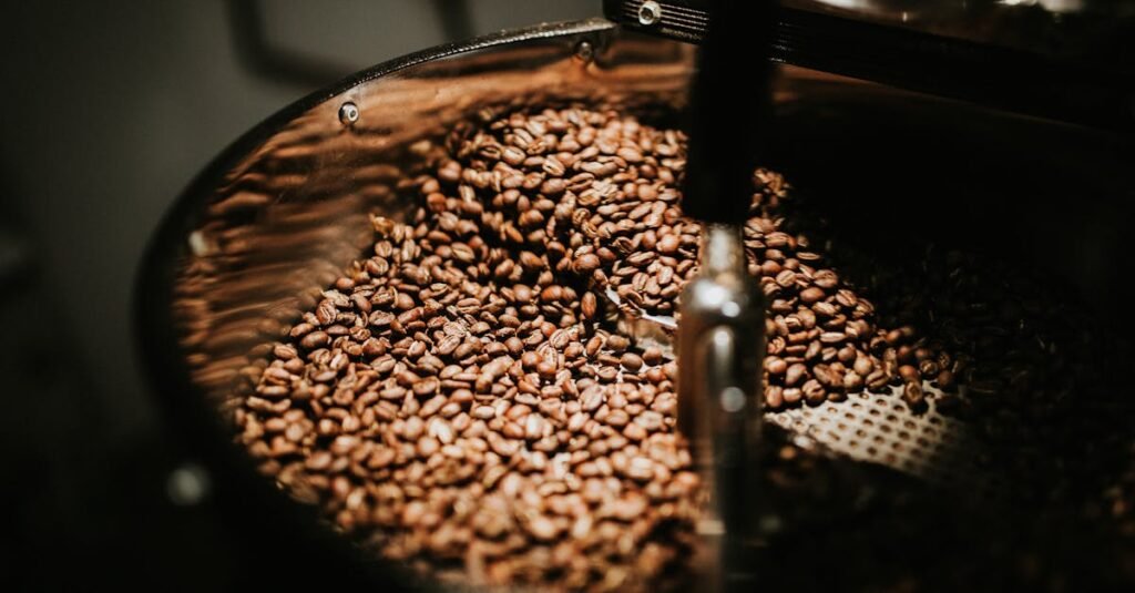 Close-up of freshly roasted coffee beans in a large industrial coffee roaster, showcasing rich textures and warm tones.
